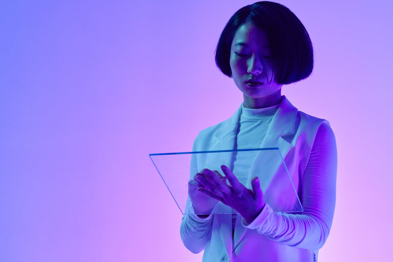 Woman interacts with a transparent digital screen in vibrant studio lighting.